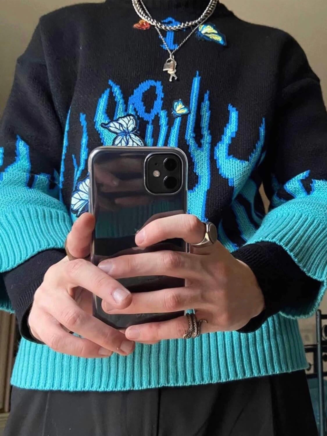 details of our black knitted sweater with blue flames that comes from the bottom of the sweater and the wrists with blue embroidered butterflies