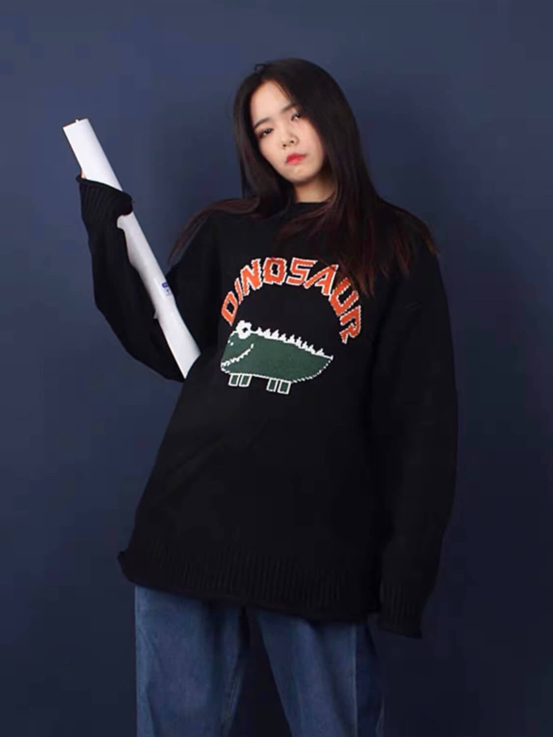 black knitted sweater with a dinosaur drawn by a child with dinosaur written in orange above the dinosaur