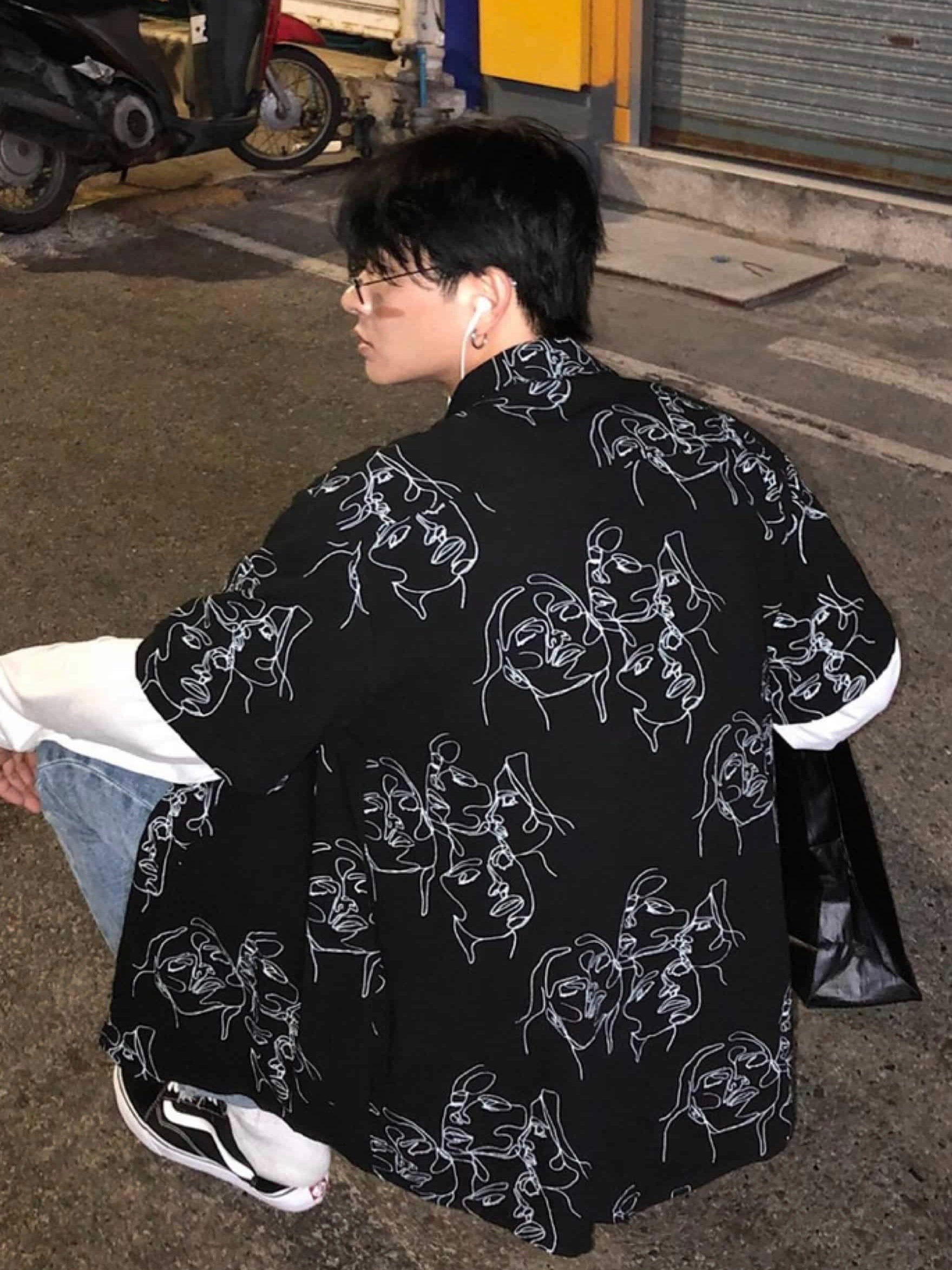 black shirt with white sketches faces back view