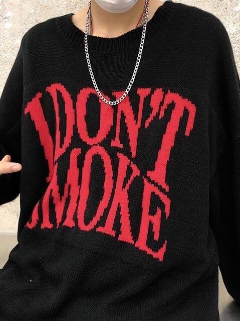 details of our black knitter sweater with I don't smoke written in big red letters on the chest