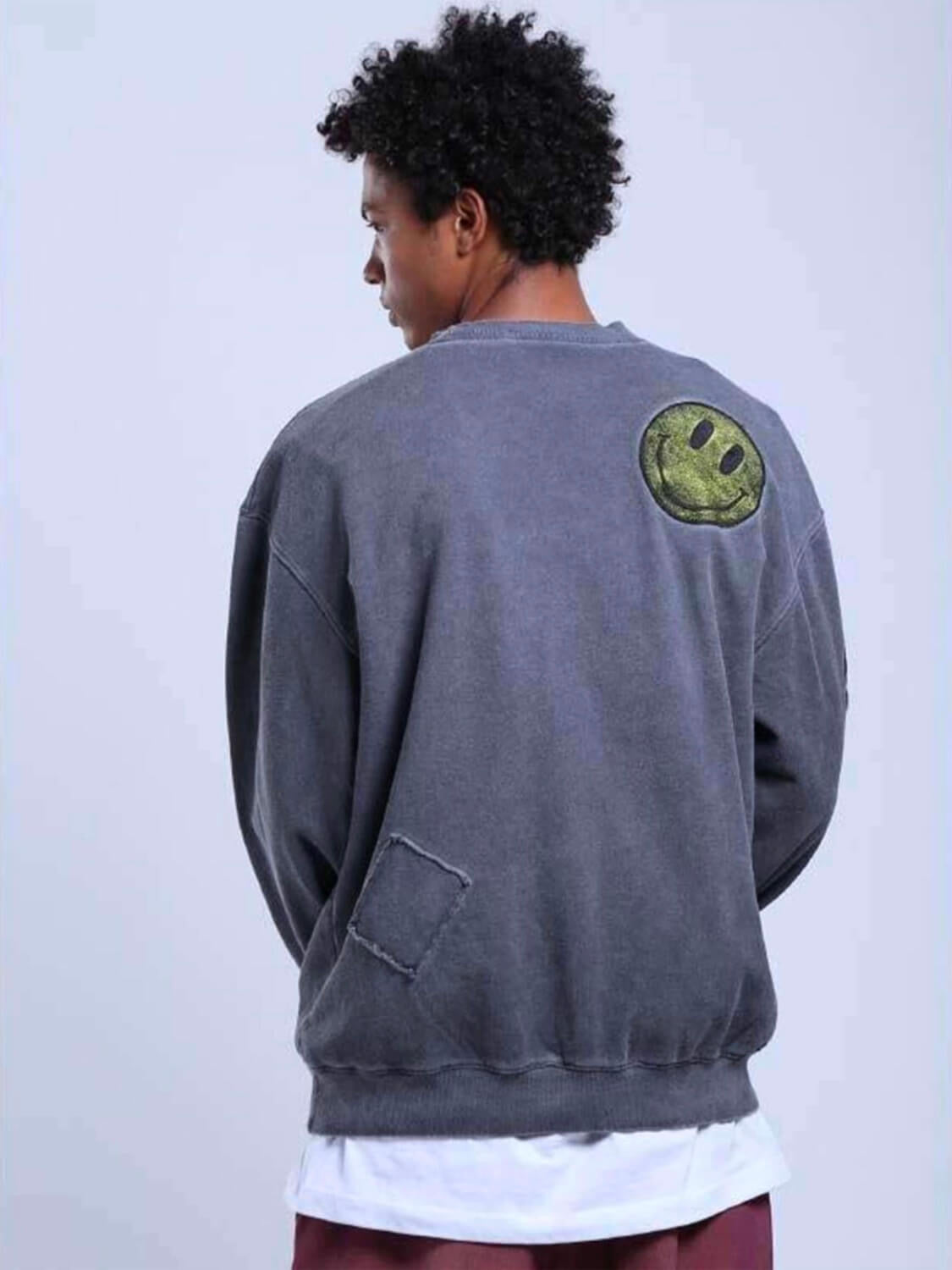 patched gray pullover with large yellow smiling faces on the sleeves and one in the upper back worn