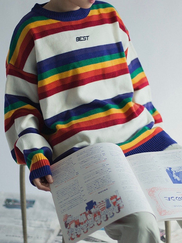 knitted sweater with rainbow lines between big white lines. Best is embroidered in black on the chest on a white line worn